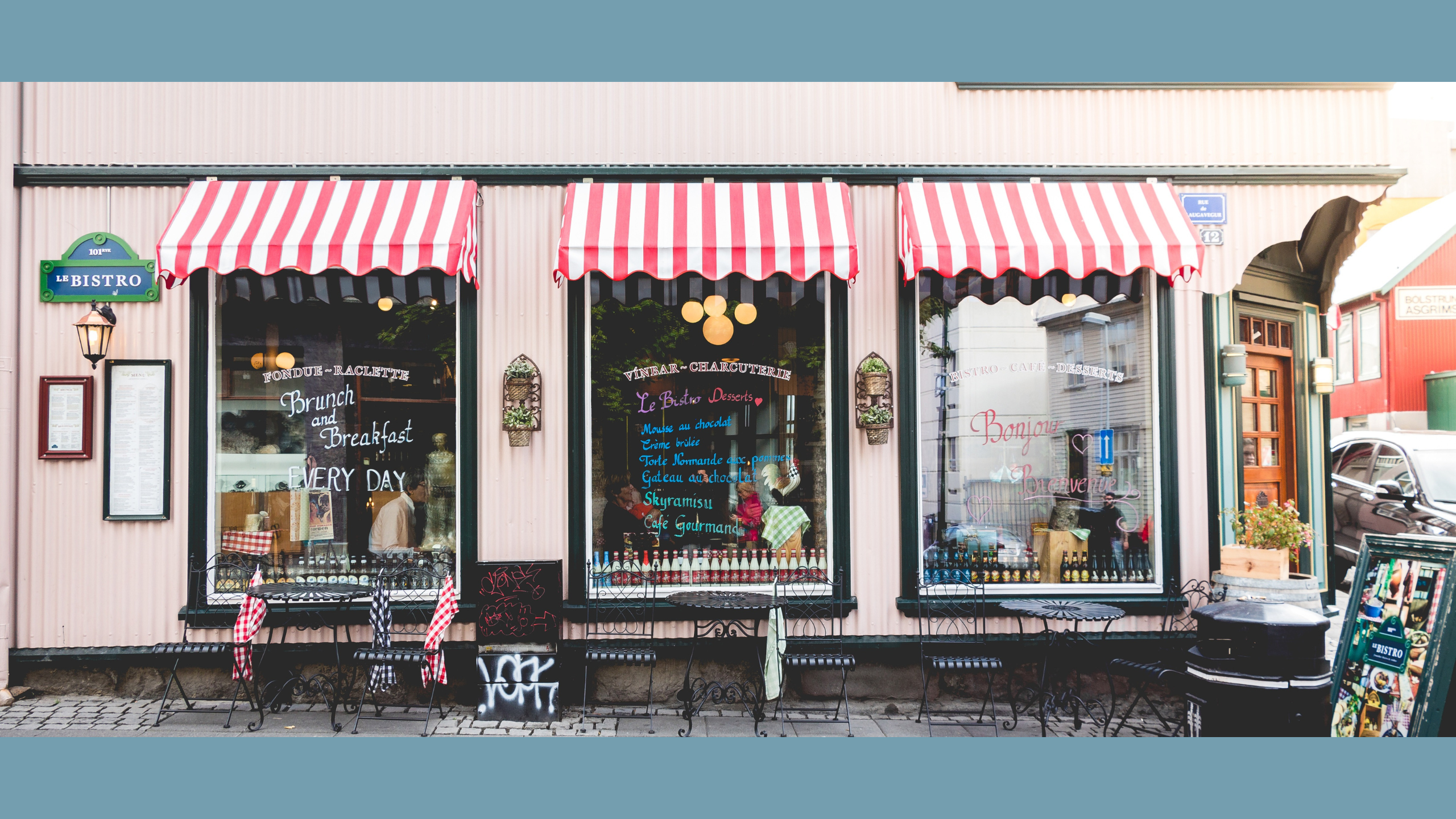 Small business, visible 3 windows with writing on them and striped awnings.
