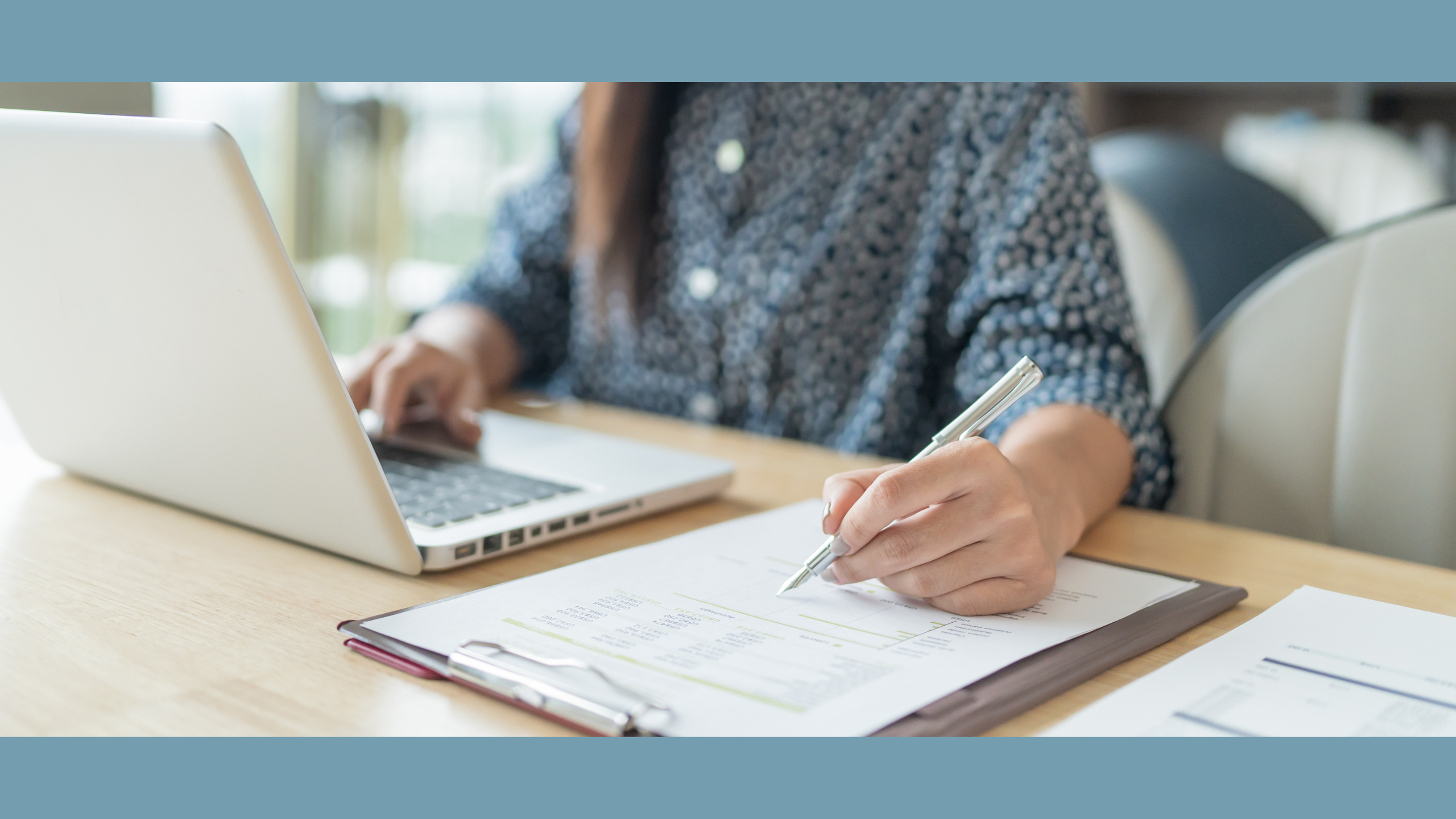A woman business owner is optimizing her budget for a PPC campaign at the desk, laptop and notebook in front of her.