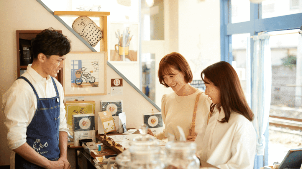 Small cafe owner watching two customers smiling while they decide what to order.